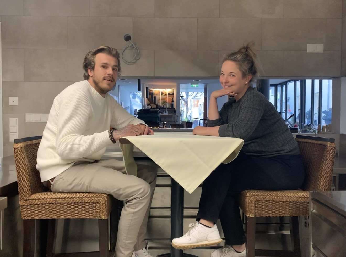 Chefkoch und Chefin auf einem Hochtisch in der Kueche sitzend