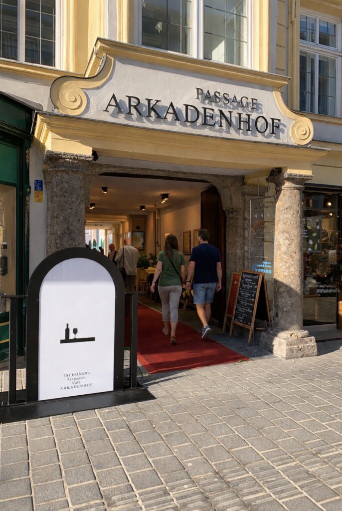 Durchgang in den Arkadenhof mit Personen und einem großen Schild am Eingang