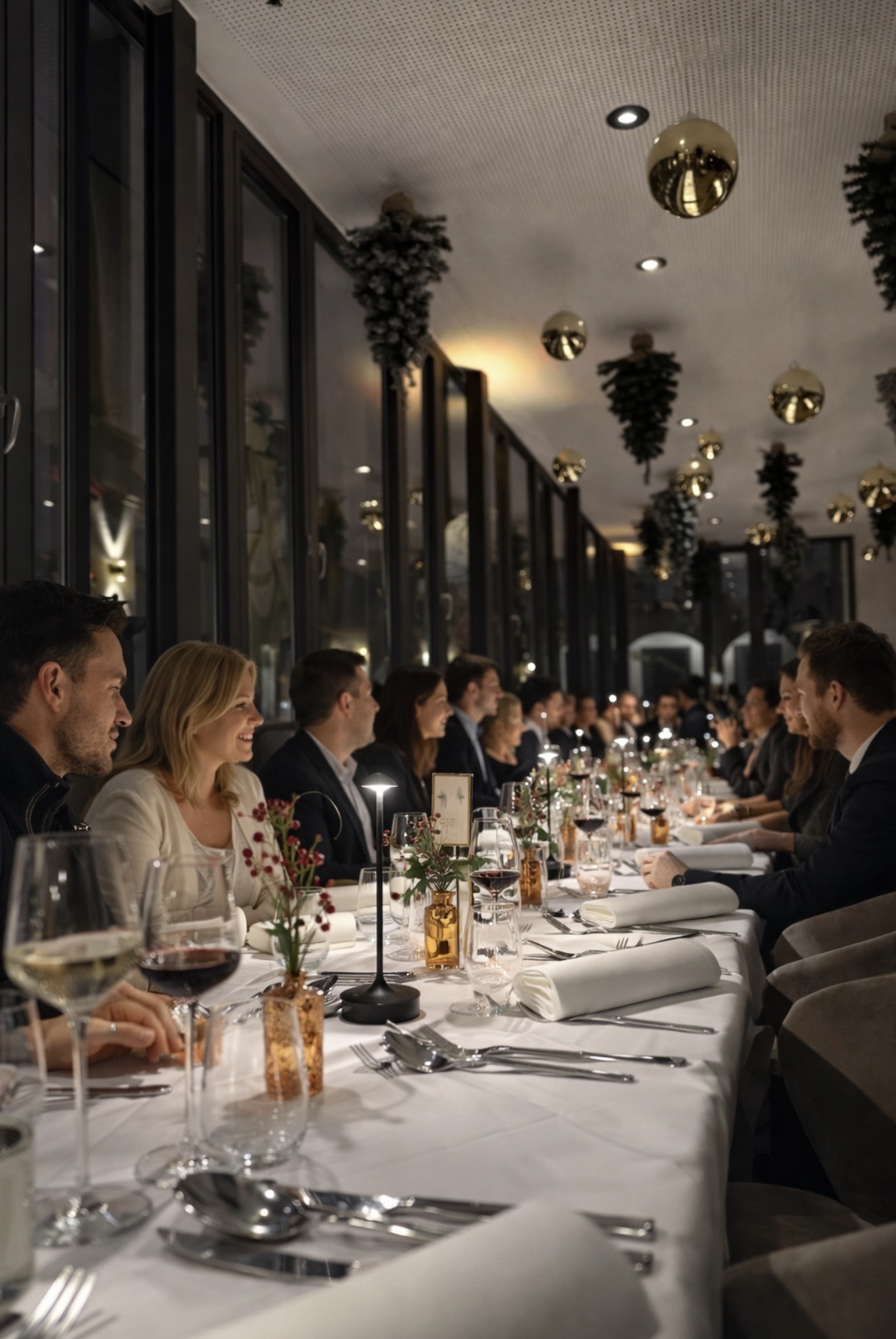 eine größere Gruppe von Menschen die einen schönen Abend im Restaurant an einer langen Tafel verbringen